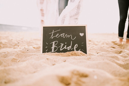 Team bride blackboard in sand