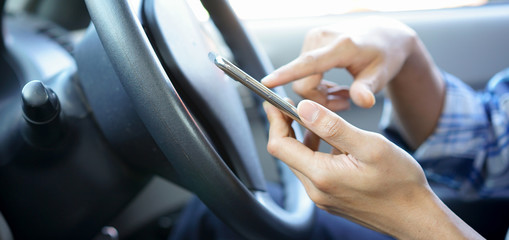 close up on businessman hand holding and using smartphone in car while driving on the road for heading to destination , transportation and technology concept