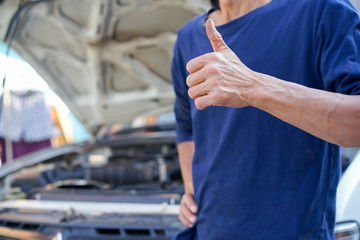 close up on technician man  hand thumb up over malfunctional car for repair concept
