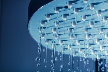 Shower Head with Water Stream on Blue Background