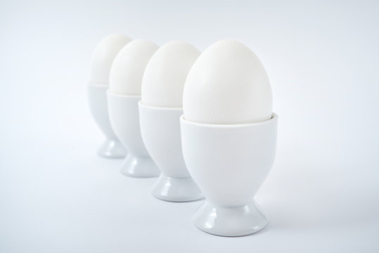 White eggs standing on egg cup isolated on white background, copy space. Row of boiled eggs in stand. Healthy food concept