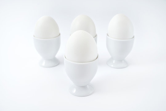 White eggs standing on egg cup isolated on white background, copy space. Boiled eggs in stand. Healthy food concept