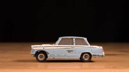 Old retro metal toy car on wooden table with black background