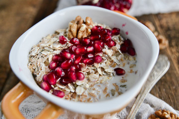 Breakfast: granola with pomegranate and walnuts on natural wooden background rustic. The concept of healthy and high-carbon nutrition.
