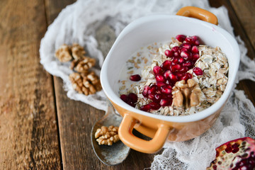 Breakfast: granola with pomegranate and walnuts on natural wooden background rustic. The concept of healthy and high-carbon nutrition.