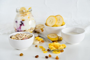 Breakfast in a jar: cereal, banana, fresh berries, granola, yogurt on a light background. The concept of healthy eating, high-carbon Breakfast.
