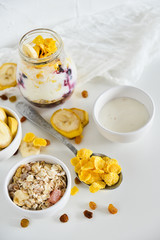 Breakfast in a jar: cornflakes, banana, fresh berries, granola, yogurt on a light background. The concept of healthy eating, high-carbon Breakfast.