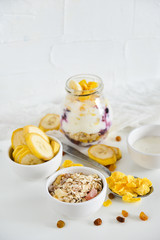 Breakfast in a jar: cornflakes, banana, fresh berries, granola, yogurt on a light background. The concept of healthy eating, high-carbon Breakfast.