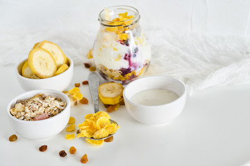 Breakfast in a jar: cornflakes, banana, fresh berries, granola, yogurt on a light background. The concept of healthy eating, high-carbon Breakfast.