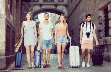 Two women and men are walking together with luggage