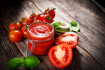 Tomato sauce and fresh tomatos on rustic background