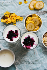 Healthy Breakfast: homemade granola, banana, fresh berries, yogurt in glass cups on light textile background. The concept of healthy eating, high-carbon Breakfast.
