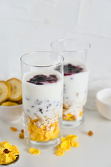 Breakfast in glass Cup: homemade granola, banana, fresh berries, yogurt on white background. The concept of healthy eating, high-carbon Breakfast.