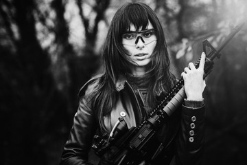 Obraz premium close-up portrait of a beautiful civilian lady with a gun in hand, creates protection of her home. The model looks ahead. Lady in tactical glasses. The concept of security. Dark background