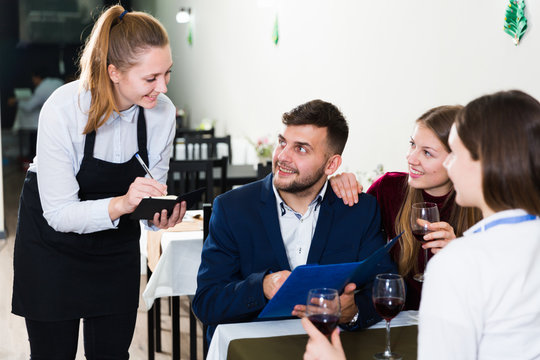 Woman waiter is taking order from clients