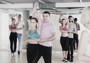 Dancing couples learning salsa at dance class
