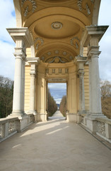 Endlos scheinender Fußweg durch eine offene Säulenhalle in einen Park in Wien
