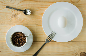 Raw egg on a plate and coffee beans in a cup