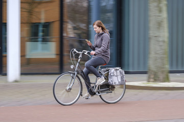 girl riding a bike and looks at her smartphone, danger