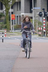 girl riding a bike and looks at her smartphone, danger