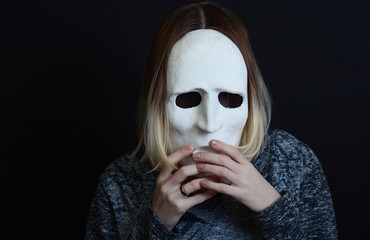 Young blonde girl holding a white theatrical mask