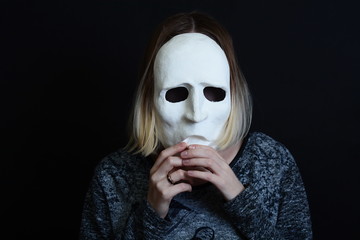 Young blonde girl holding a white theatrical mask