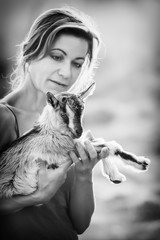 Black and white photo with beautiful woman  and small goatling on her hands