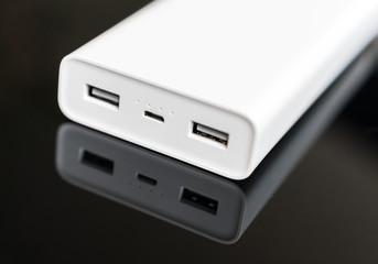 White power bank on mirrored surface. Space for your text.