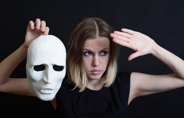 Actress in black dress holding a white theatrical mask