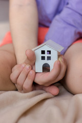Small kid hands holding white house building.