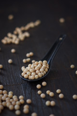 Soy beans on black background in ceramic spoon.