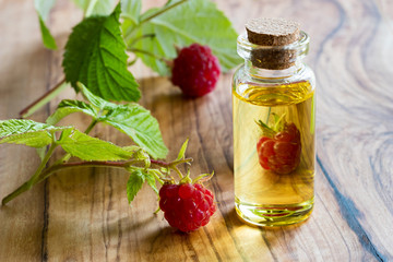 Obraz na płótnie Canvas Fresh raspberries with a bottle of raspberry seed oil
