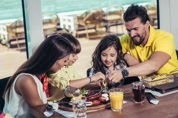 Father and mother with children enjoying meal in restaurant.