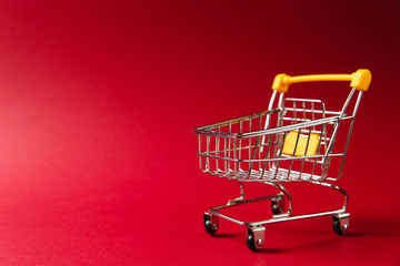 Close up of supermarket grocery push cart for shopping with black wheels and yellow plastic...