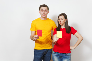 European serious severe young woman and man, football referee hold choose yellow and red soccer...