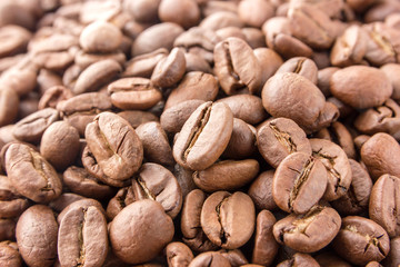 Coffee grains are scattered all over the surface. Roasted coffee beans close-up.
