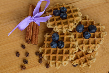Belgian waffles with fresh berries, coffee beans and cinnamon on a cutting board wooden background