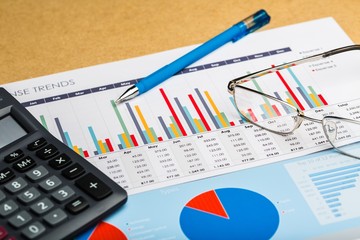 Pen, Eyeglasses and Calculator on Business Graphs and Charts
