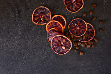 Fototapeta na wymiar Beautiful and tasty background for design. Dried red orange slices with a coffee beans on a stone background. Cuisine wallpaper.