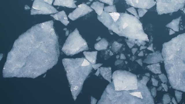 Cracked Ice floes slowly drifting through the dark water of the Copenhagen canal - filmed from above