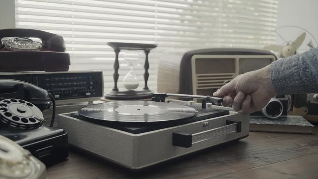 Man playing a vinyl record and vintage objects