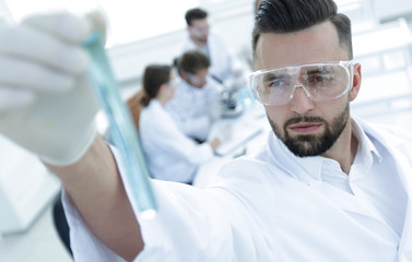 image is blurred. young scientist holding tube with the reagents