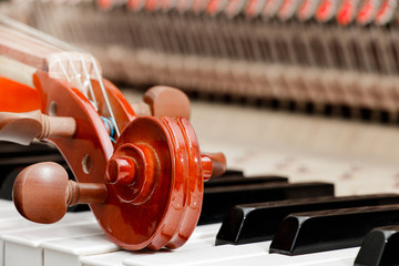 classic brown violin on the close up image of grand piano keys and interior showing strings, hammer...