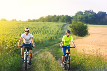 Fototapeta premium young man and woman are driving their bicycles on their way to the field in the summer.