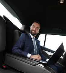 successful man working with laptop sitting in car