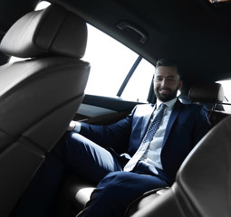 businessman talking on the phone while sitting in the back seat of his car
