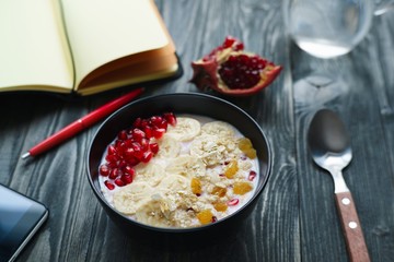 Day planning, time management, healthy food and lifestyle concept. Tasty  oatmeal and yoghurt smoothie bowl with fruits for breakfast on table with paper planner.