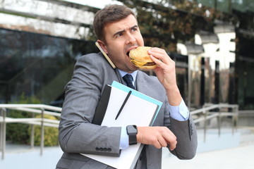 Overworked businessman eating fast food on the go