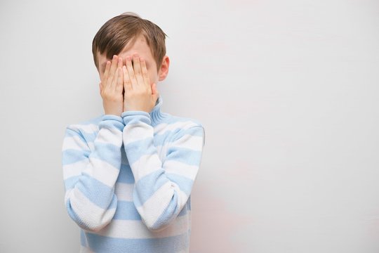 Frightened Scared Boy Closing His Face With Hands.