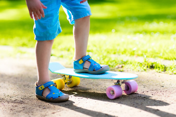 Child riding skateboard in summer park